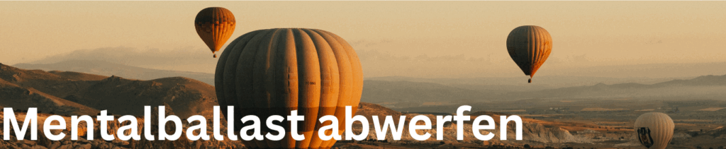 Banner mit Schrift "Mentalballast abwerfen". Heißluftballons in Bergen.