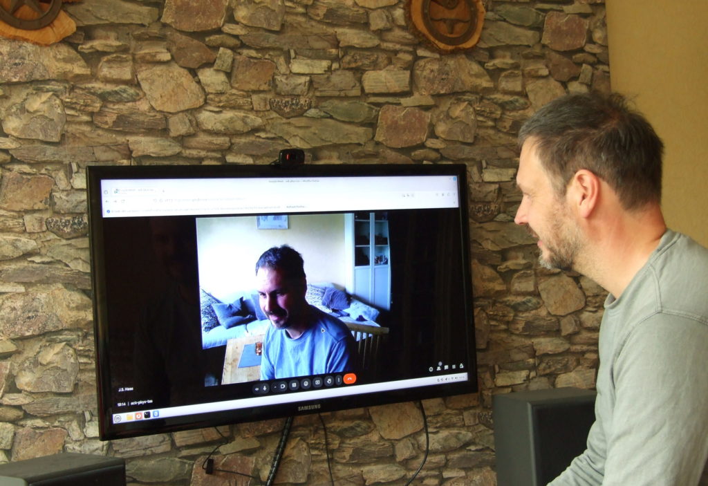 Online-Coaching Szenariio. Jan Soeren schaut auf einen großen Bildschirm einer Videokonferenz.