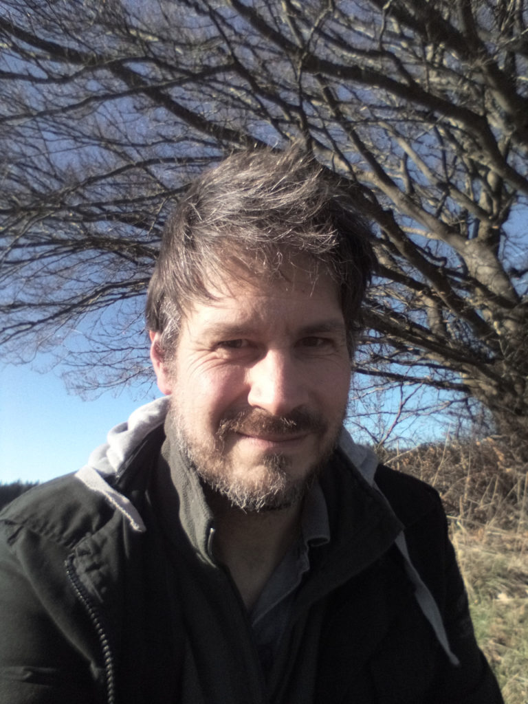Profilfoto: Jan Soeren in der Natur. Im Hintergrund ein knorriger Baum auf einer Wiese.